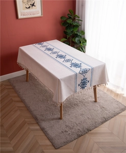 Close-up of blue floral embroidery and fringe details on a rectangle linen tablecloth