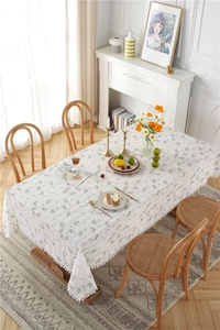 Detail of floral cotton tablecloth featuring cream jacquard fabric and tassel ball edges