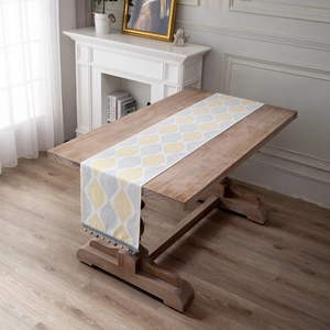 Modern chenille table runner with yellow leaf patterns and decorative bead tassels