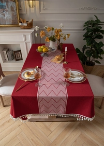 Detail of burgundy polyester jacquard tablecloth with geometric pattern and white tassels