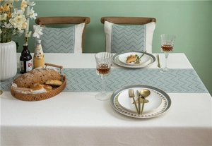 Detail of sage green wave pattern table runner on a cream textured jacquard tablecloth