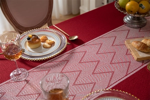 Detailed texture of red jacquard tablecloth and white geometric patterned table runner