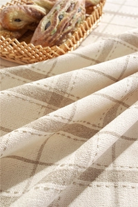 Close-up of geometric plaid tablecloth texture with rustic fringe detail in warm lighting