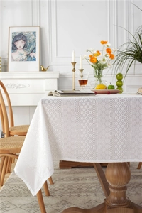Close-up of white floral lace tablecloth with hollow patterns on a wooden table