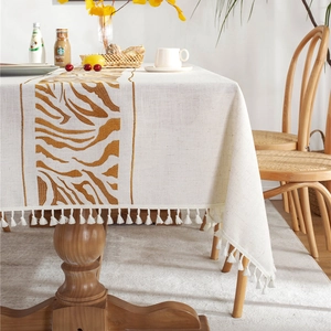 Modern cream linen tablecloth with brown tiger stripes and tassel edges on dining table