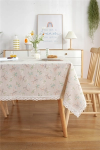 Detailed close-up of beige floral lace tablecloth with orange rose pattern and white border