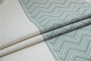 Macro detail of wave jacquard tablecloth with zigzag patterns and soft fringe trim