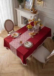 Detailed view of red vintage tablecloth with white tassel trim and woven geometric pattern