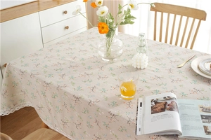 Detail of beige floral tablecloth with intricate white lace border on a wooden table