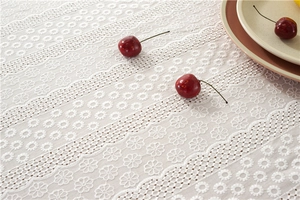 Close-up of white cotton lace tablecloth with floral embroidery and hollowed-out wavy edges