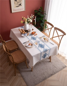 Detail of embroidered tablecloth with blue vintage patterns and handmade tassels on edges