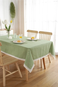 Detailed view of green polka dot tablecloth with delicate white lace trim on wooden table