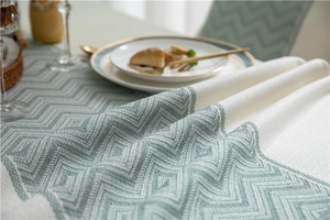 Detailed view of sage green wavy jacquard tablecloth fabric with woven texture and fringe