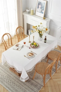 Detail of white cotton tablecloth showing delicate floral lace edge and jacquard texture