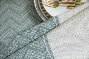 Close-up of woven jacquard tablecloth featuring green herringbone and cream diamond patterns