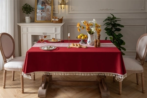 Detail of burgundy jacquard tablecloth with white tassel edge and elegant floral table runner