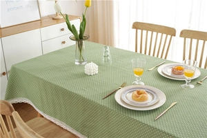 Detailed view of green tablecloth with white polka dots and delicate lace trim edge
