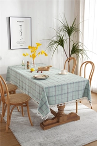 Detail of light blue and purple checkered tablecloth with white ball fringe on a wooden table
