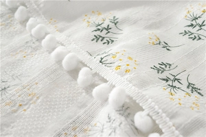 Detailed macro view of white cotton lilac jacquard fabric with pom-pom fringe trim