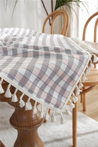 Detail of Nordic plaid tablecloth with grey and pink checks and white fringe tassels