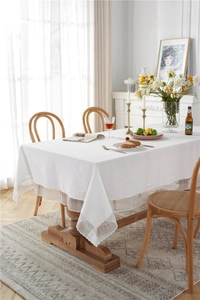 Detail of white cotton tablecloth with romantic meteor lace edges in a sunlit dining room