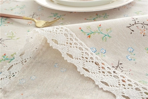 Detailed close-up of floral cotton linen tablecloth with delicate white lace edge