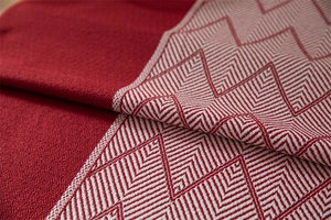 Macro view of geometric wave pattern and fringed edges on red jacquard tablecloth