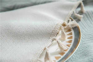Close-up of cream jacquard tablecloth with geometric diamond texture and fringe trim