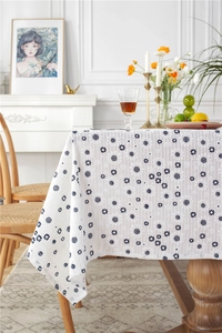 Detailed view of white cotton tablecloth featuring blue floral patterns and striped texture
