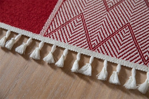 Close-up of red and white geometric jacquard tablecloth with elegant tassel edges