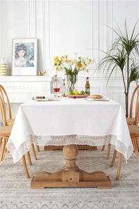 Close-up of elegant white cotton tablecloth with delicate geometric lace edge on wood table