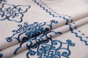Close-up of intricate navy blue floral embroidery on a premium beige cotton linen tablecloth