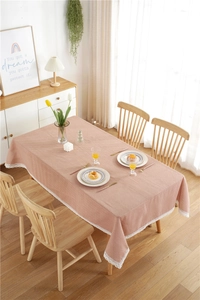 Pink polka dot tablecloth with white lace edges on a modern wooden dining table
