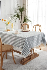 Detailed close-up of green and white plaid tablecloth with elegant white fringe tassels
