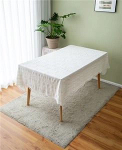Close-up of white cotton tablecloth featuring textured jacquard and pom-pom tassel trim