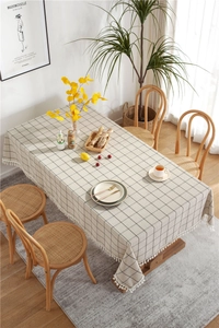 Detail of checkered rectangle tablecloth with tassels on a wooden dining table