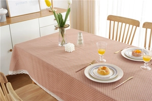 Close-up of pink polka dot tablecloth featuring white lace edges on a wooden table