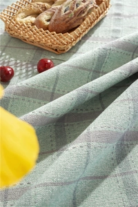 Detailed view of Nordic style green checkered tablecloth with textured weaving and tassels