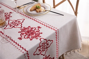 Close-up of geometric red embroidery and off-white tassels on linen tablecloth