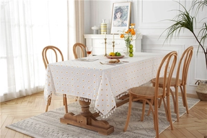 Close-up of yellow polka dots and white fringe detail on a rectangular cotton tablecloth