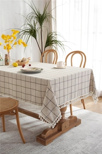 Close-up of beige linen tablecloth with black grid pattern and white fringe details