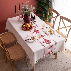Close-up of rectangular cream cotton linen tablecloth with red floral embroidery and tassels
