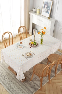 Detail of white cotton tablecloth with orange polka dots and white tassel fringe edges
