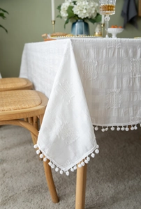 Detail of white rectangle tablecloth with pom-pom trim and jacquard texture finish