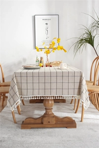 Macro detail of beige plaid tablecloth featuring cotton linen fabric and white fringe tassels