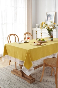 Close-up of ginger yellow cotton tablecloth with white lace edges and rustic texture