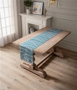 Close-up of blue geometric chenille table runner with decorative ball fringe tassels