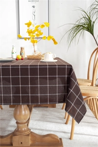 Macro detail of the brown plaid tablecloth fabric texture in a cozy home setting