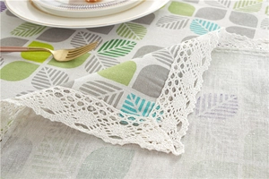 Detail showing pastoral leaf patterns and fine white lace edges on cotton-linen tablecloth