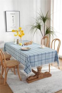 Close-up of blue lattice linen tablecloth featuring thick white tassels and woven texture